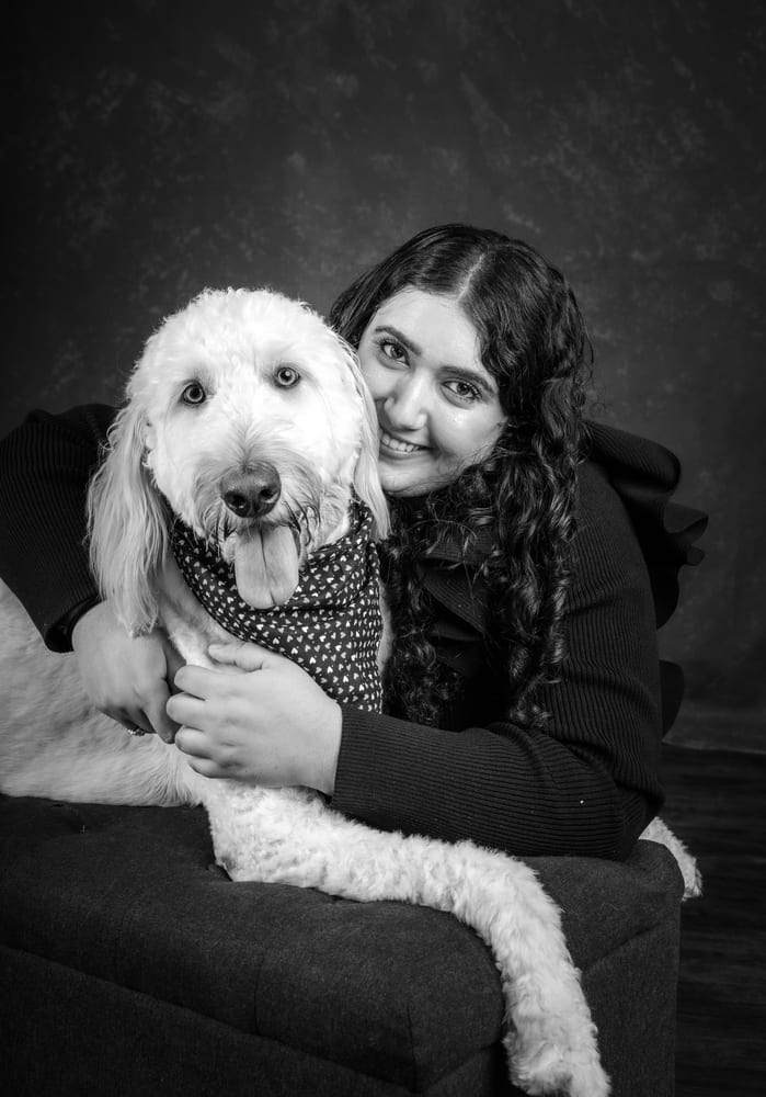 Nadia and her doodle on the sofa, both smiling